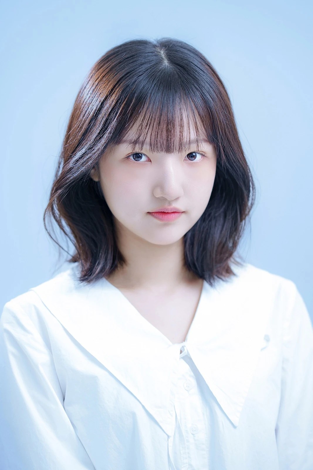 밝은 푸른색 배경에서 촬영한 여성 프로필사진